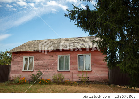 Old pink wooden house surrounded by green trees in the countryside 138570803