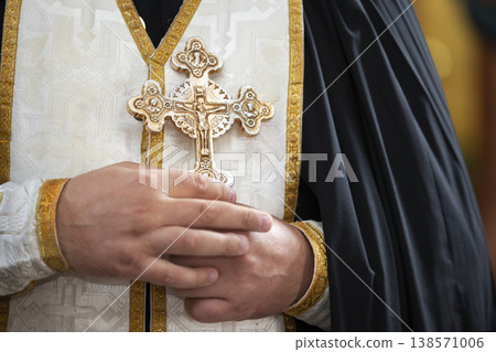 Cleric holding a decorated cross during a religious ceremony in a historic church setting 138571006