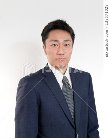 A Japanese man in a suit with a serious expression. 138571025