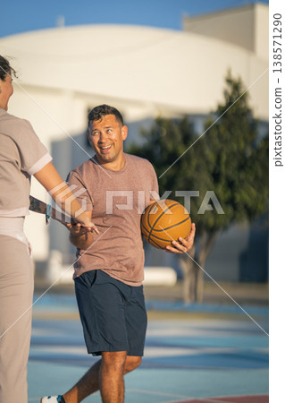 Man holding basketball interacting on outdoor court Man holding basketball interacting on outdoor court 138571290
