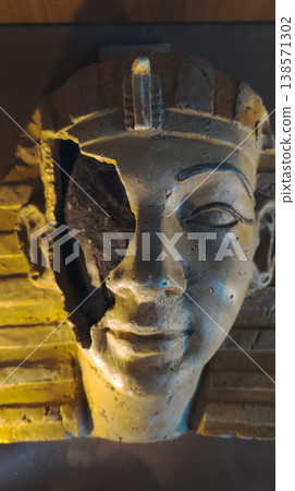 Ancient egyptian pharaoh mask or mummy head exhibit in a museum, featuring a broken face detail with visible inner layers, golden textures, and dramatic lighting. Ancient egyptian pharaoh mask or mummy head exhibit in a museum, featuring a broken face detail with visible inner layers, golden textures, and dramatic lighting. 138571302