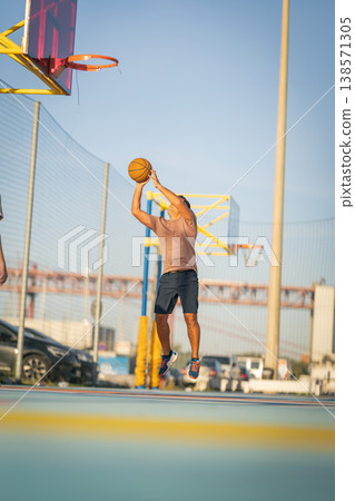Young man playing basketball, shooting ball on court Young man playing basketball, shooting ball on court 138571305