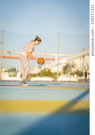 Woman dribbling basketball on colorful outdoor court Woman dribbling basketball on colorful outdoor court 138571321
