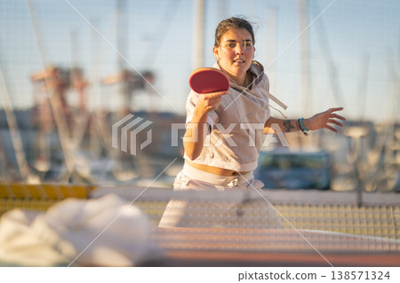 Young woman playing table tennis in outdoor marina Young woman playing table tennis in outdoor marina 138571324