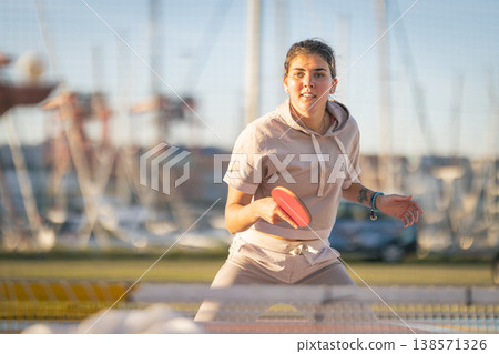 Young woman playing table tennis outdoors in marina Young woman playing table tennis outdoors in marina 138571326