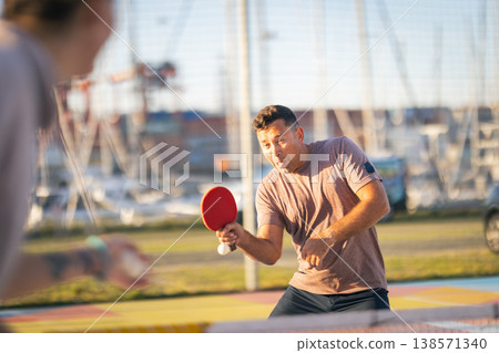 Man concentrating playing table tennis outdoors Man concentrating playing table tennis outdoors 138571340