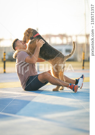 Man and airedale terrier dog embracing on court Man and airedale terrier dog embracing on court 138571357
