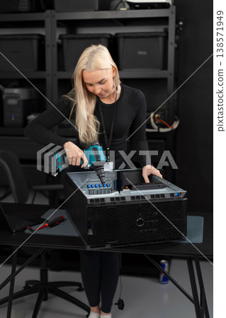 Female IT technician in her 20s upgrades and clean a server with dust blower in a lab Female IT technician in her 20s upgrades and clean a server with dust blower in a lab 138571949