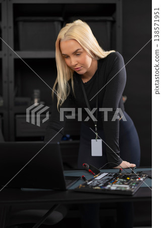 Female IT technician with laptop and hardware setup performing diagnostics and repair Female IT technician with laptop and hardware setup performing diagnostics and repair 138571951
