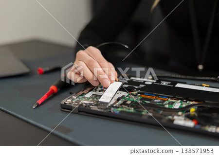 IT technician in his thirties repairs a laptop internals, upgrading components and diagnosing hardware issues IT technician in his thirties repairs a laptop internals, upgrading components and diagnosing hardware issues 138571953