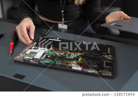 Female IT technician in her 20s repairs a laptop motherboard during a professional repair session Female IT technician in her 20s repairs a laptop motherboard during a professional repair session 138571954