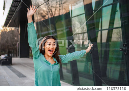 Young businesswoman celebrating success in front of modern office building Young businesswoman celebrating success in front of modern office building 138572138