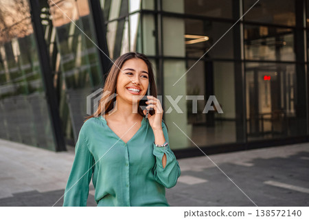 Young businesswoman talking on phone and smiling near office building Young businesswoman talking on phone and smiling near office building 138572140