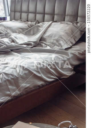 Grey silk sheet on a bed. Luxury bed linen. Hotel bedroom concept. Comfortable bed with fabric and two pillows. Double bed for couple. Rumpled bedding after sleeping. Two pillows on the sofa. Grey silk sheet on a bed. Luxury bed linen. Hotel bedroom concept. Comfortable bed with fabric and two pillows. Double bed for couple. Rumpled bedding after sleeping. Two pillows on the sofa. 138572220