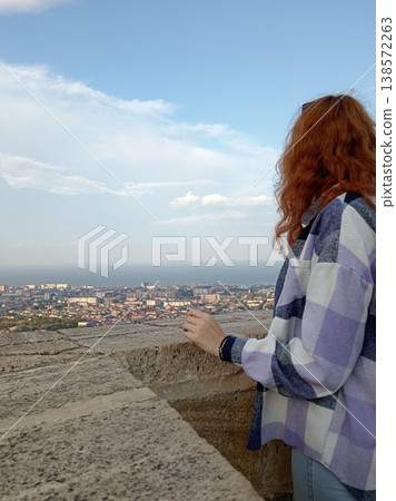 Young female tourist with long curly red hair admiring aerial view of Derbent from ancient Naryn-Kala fortress, Dagestan, Russia Young female tourist with long curly red hair admiring aerial view of Derbent from ancient Naryn-Kala fortress, Dagestan, Russia 138572263