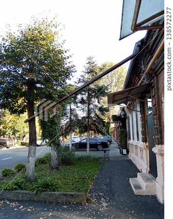 Bright summer day on a cozy street in Vladikavkaz, North Ossetia, Russia. Shaded sidewalk with historic architecture and blooming greenery Bright summer day on a cozy street in Vladikavkaz, North Ossetia, Russia. Shaded sidewalk with historic architecture and blooming greenery 138572277