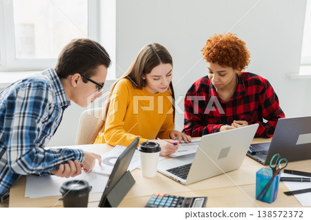 Teamwork brainstorm. Diverse colleagues working together discuss financial statistics. Group of happy young modern people sitting in creative office discussing business. Young professional team Teamwork brainstorm. Diverse colleagues working together discuss financial statistics. Group of happy young modern people sitting in creative office discussing business. Young professional team 138572372