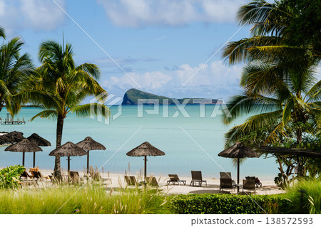 Empty sunbeds and umbrellas on tropical beach in Mauritius resort. Empty sunbeds and umbrellas on tropical beach in Mauritius resort. 138572593