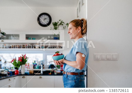 Mature woman with CGM glucose sensor preparing healthy meal at home kitchen. 138572611