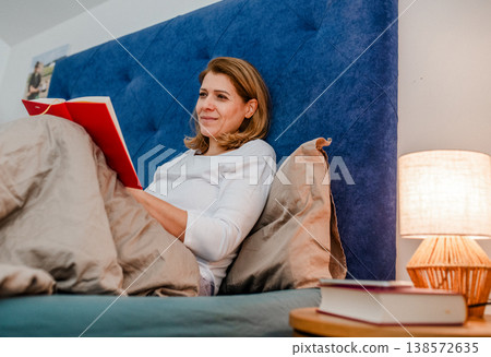 Nighttime routine for mature woman, reading book. 138572635