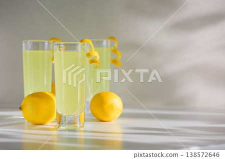 Limoncello Glasses with Curled Lemon Peels and Fresh Lemons. Limoncello Glasses with Curled Lemon Peels and Fresh Lemons. 138572646