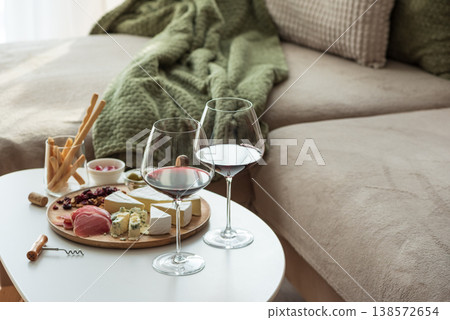 Cozy living room with two glasses of red wine and cheese on table Cozy living room with two glasses of red wine and cheese on table 138572654