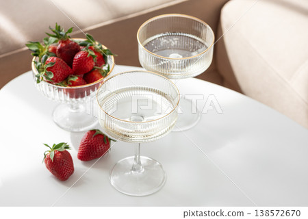 Champagne Glasses with Strawberries on White Table into Cozy Living Room Champagne Glasses with Strawberries on White Table into Cozy Living Room 138572670