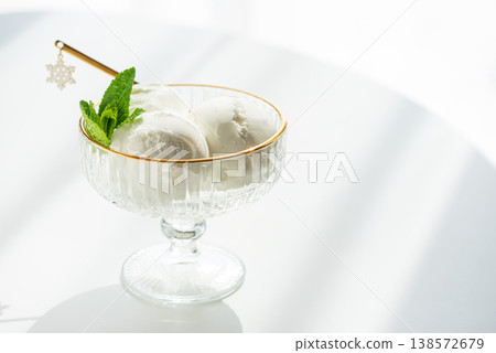 Vanilla Ice Cream in Elegant Glass Bowls on White Table with Sunlight 138572679