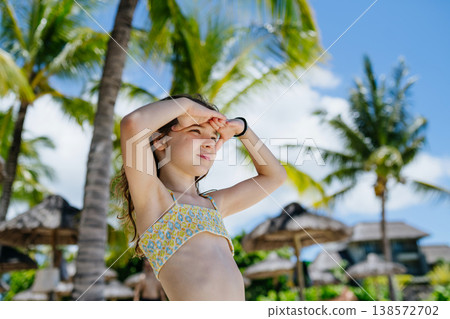 Smiling girl under palm trees during tropical family vacation. Smiling girl under palm trees during tropical family vacation. 138572702