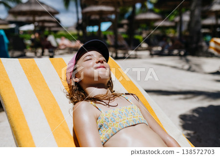Girl relaxing on sun lounger at beach resort. 138572703