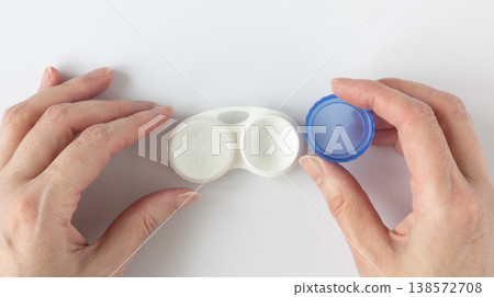 Human hands unscrew the lid of a contact lens case Human hands unscrew the lid of a contact lens case 138572708