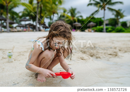 Little girl playing with sand and water on tropical beach. Little girl playing with sand and water on tropical beach. 138572726