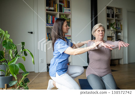 Physiotherapist helping senior woman during rehabilitation exercise at home. 138572742