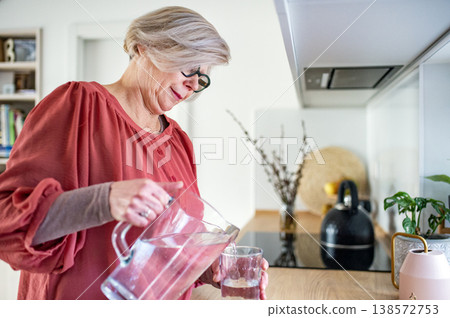 Senior woman pouring fresh water into glass. 138572753