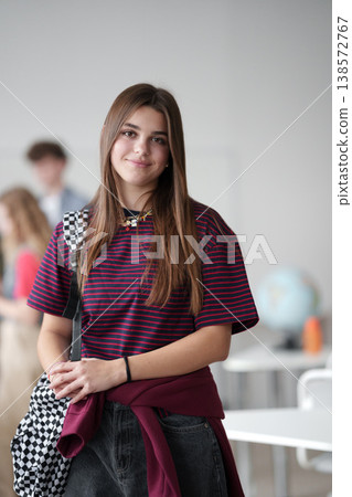 Confident teen student standing in modern classroom. Confident teen student standing in modern classroom. 138572767