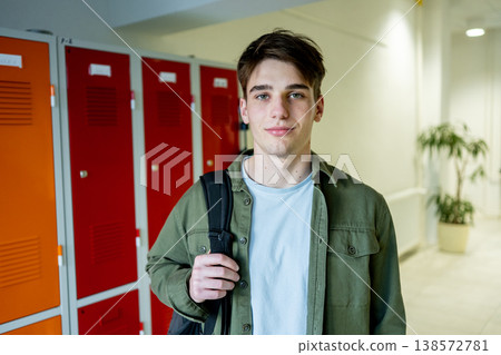 Teen student standing by lockers in school hallway. 138572781