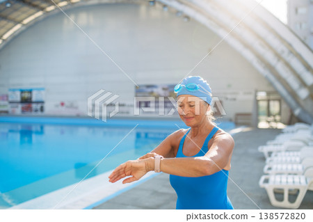 Older female swimmer stretching before swim in pool. Older female swimmer stretching before swim in pool. 138572820