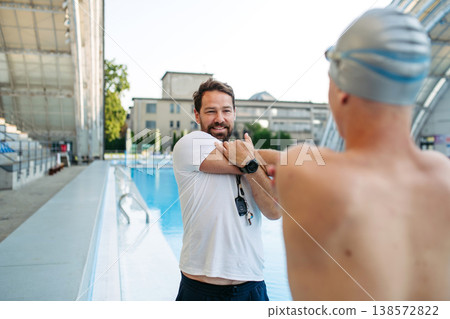 Coach preparing young swimmer for competition, stretching arms. Coach preparing young swimmer for competition, stretching arms. 138572822