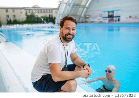 Coach giving advice to young swimme in water, standing by pool. Coach giving advice to young swimme in water, standing by pool. 138572828