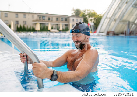 Male swimmer getting out of the pool after swim training. Male swimmer getting out of the pool after swim training. 138572831