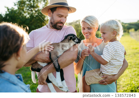 Family petting little goat at farm. 138572843