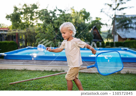 Smiling blond child playing in garden during warm summer day. 138572845