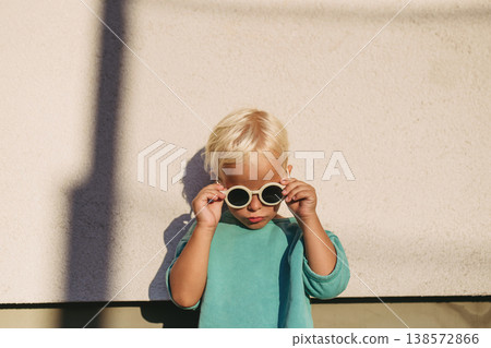 Smiling blond child wearing round sunglasses in warm sunlight. Smiling blond child wearing round sunglasses in warm sunlight. 138572866