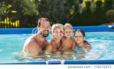 Young family with two children in swimming pool outdoors in backyard garden. 138572873