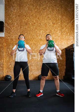 Couple doing kettlebell fitness training in a gym 138572967