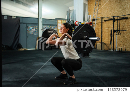 Woman doing front squat exercise with barbell in gym Woman doing front squat exercise with barbell in gym 138572979