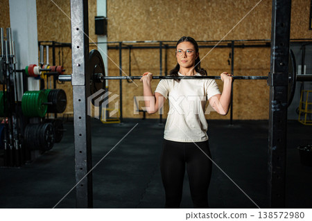 Woman exercising with barbell in gym for fitness training Woman exercising with barbell in gym for fitness training 138572980
