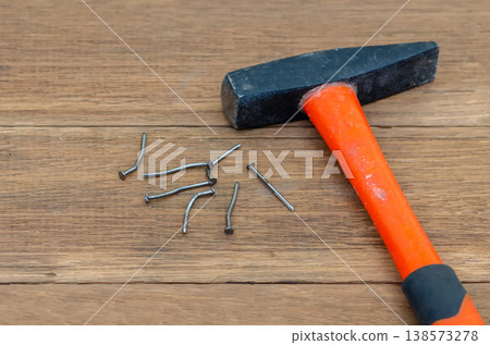 Hammer near bent nails on wooden surface showing construction failure and damage Hammer near bent nails on wooden surface showing construction failure and damage 138573278