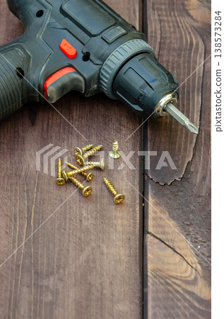 Cordless drill and screws on wooden surface close up Cordless drill and screws on wooden surface close up 138573284