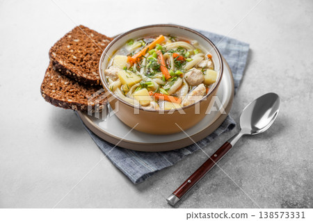 Chicken noodle soup with fresh dill in a bowl on a light textured background Chicken noodle soup with fresh dill in a bowl on a light textured background 138573331